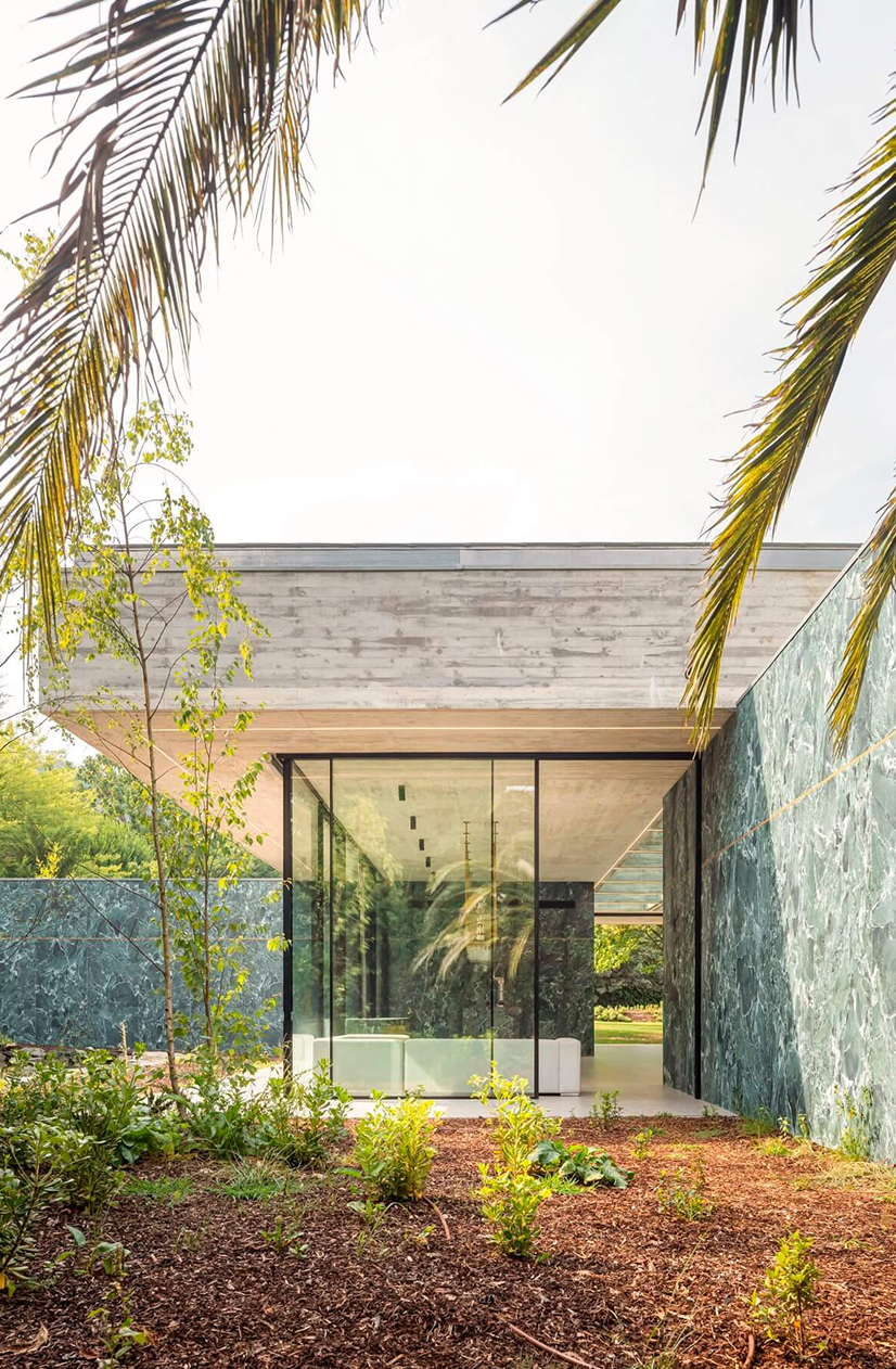 Pavilion in the Garden, Paredes: narrow glazed passage between two enclosed volumes, seen from the planted garden