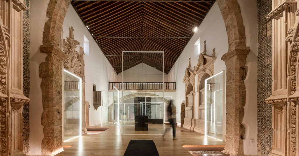 Nave of the Panteão dos Almeida in Abrantes, with glass frames and lines of light on a pine floor