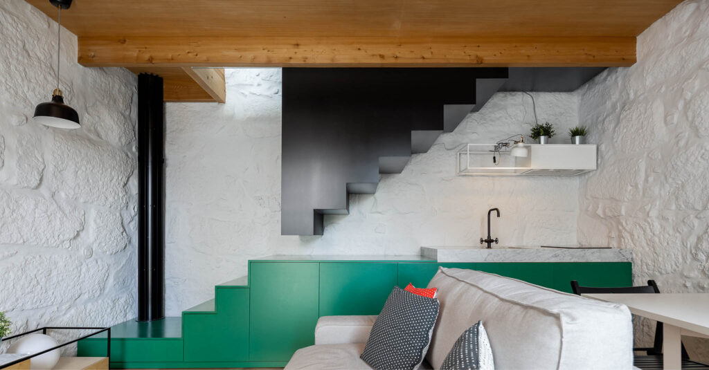 Living room and kitchen of Covelo House in Porto, a green counter turning into a black staircase