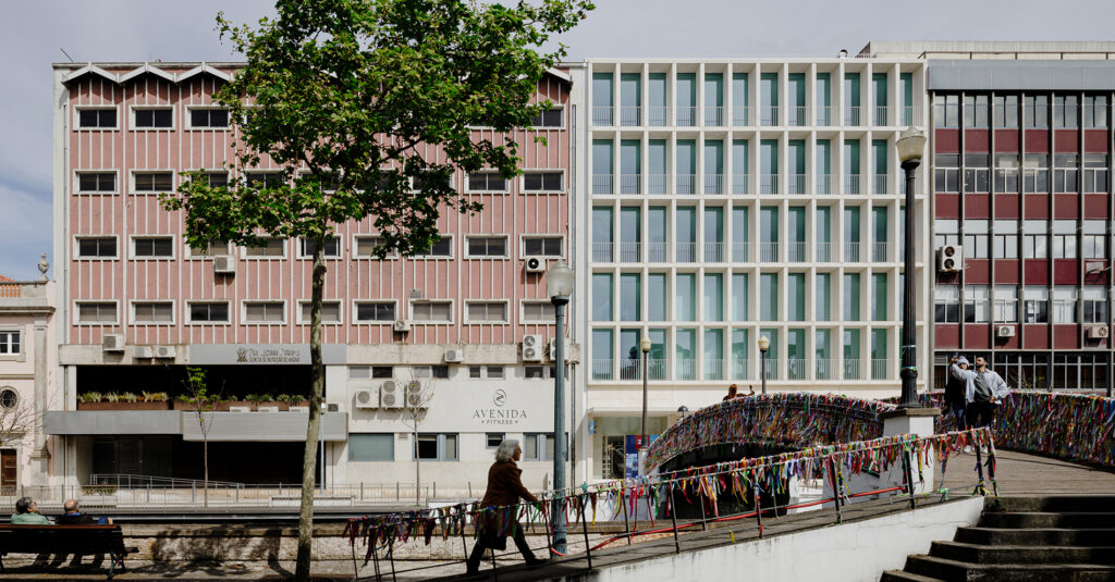 White Aveiro building in Aveiro seen from the canal bridge, its white grid facade between two older blocks