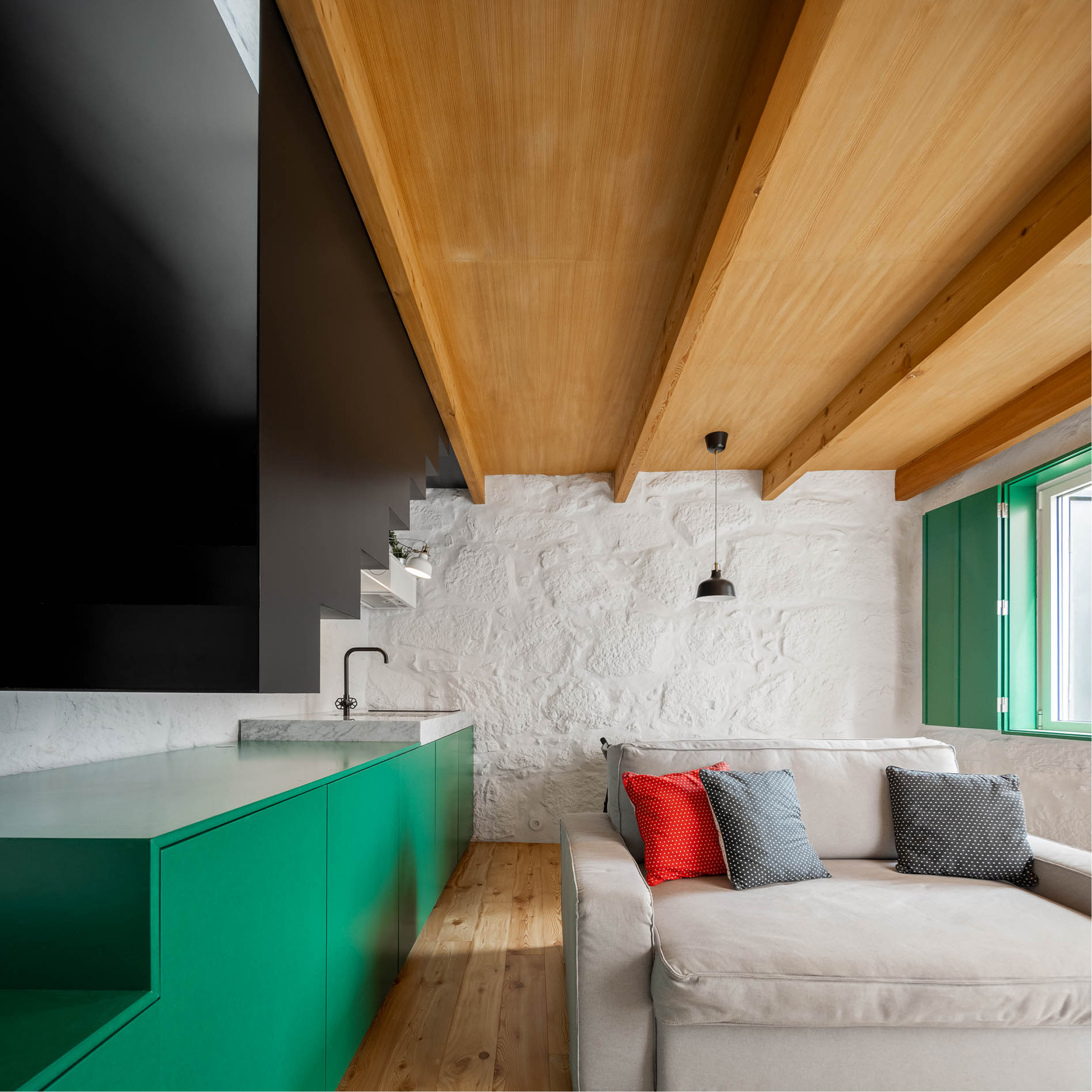 Covelo House, Porto: sofa beside the green kitchen unit, under the timber ceiling and next to a shuttered window