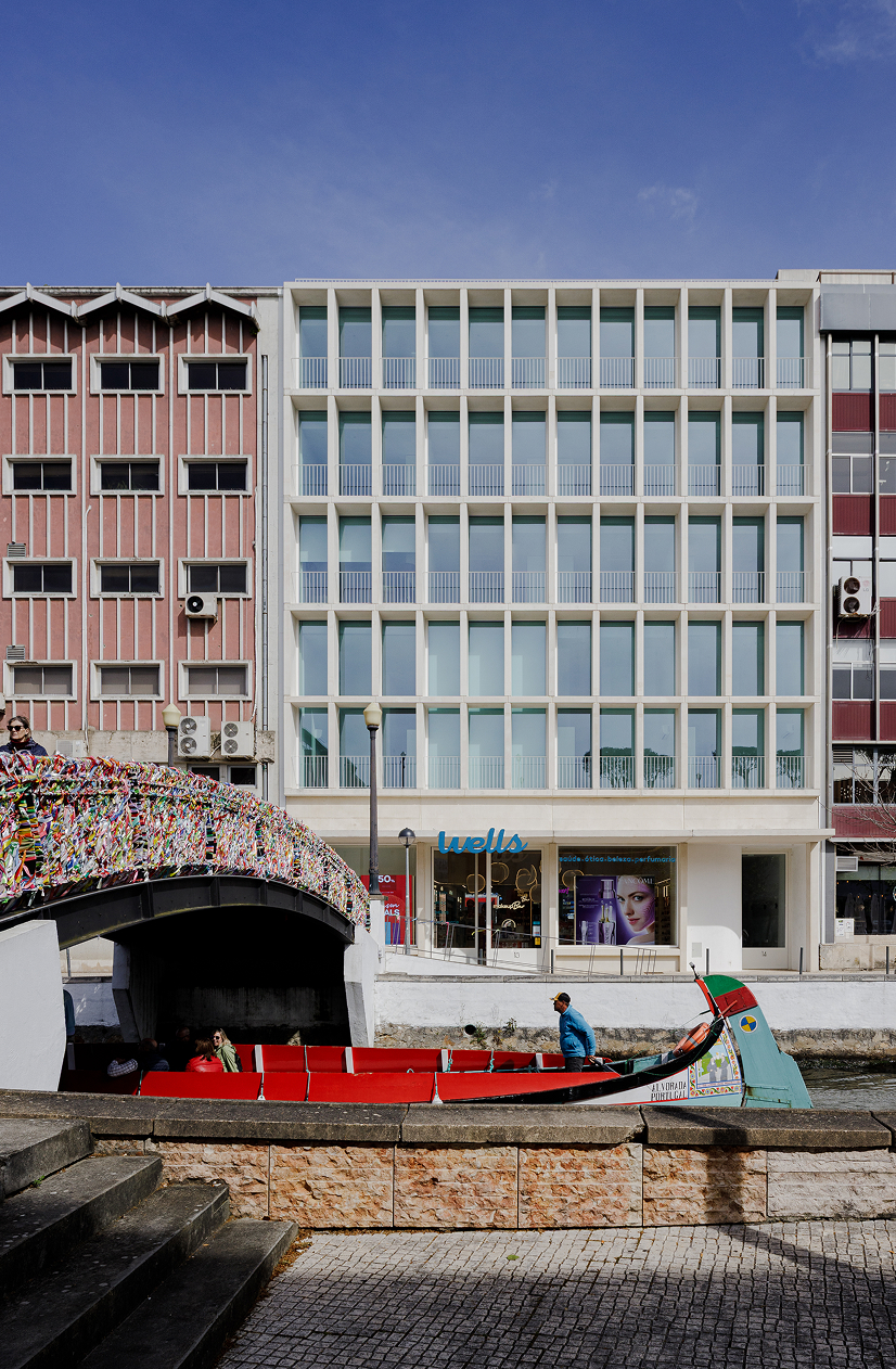 White Aveiro: building front seen across the Aveiro canal, with a red moliceiro boat and the bridge in the foreground