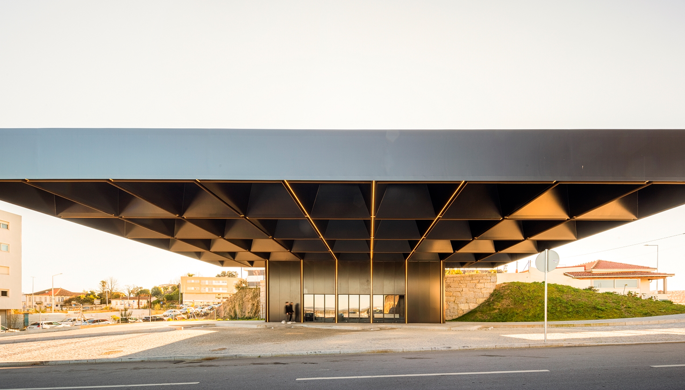 Lousada Intermodal Hub: frontal view of the long dark roof edge, the waiting volume and the road running in front of it