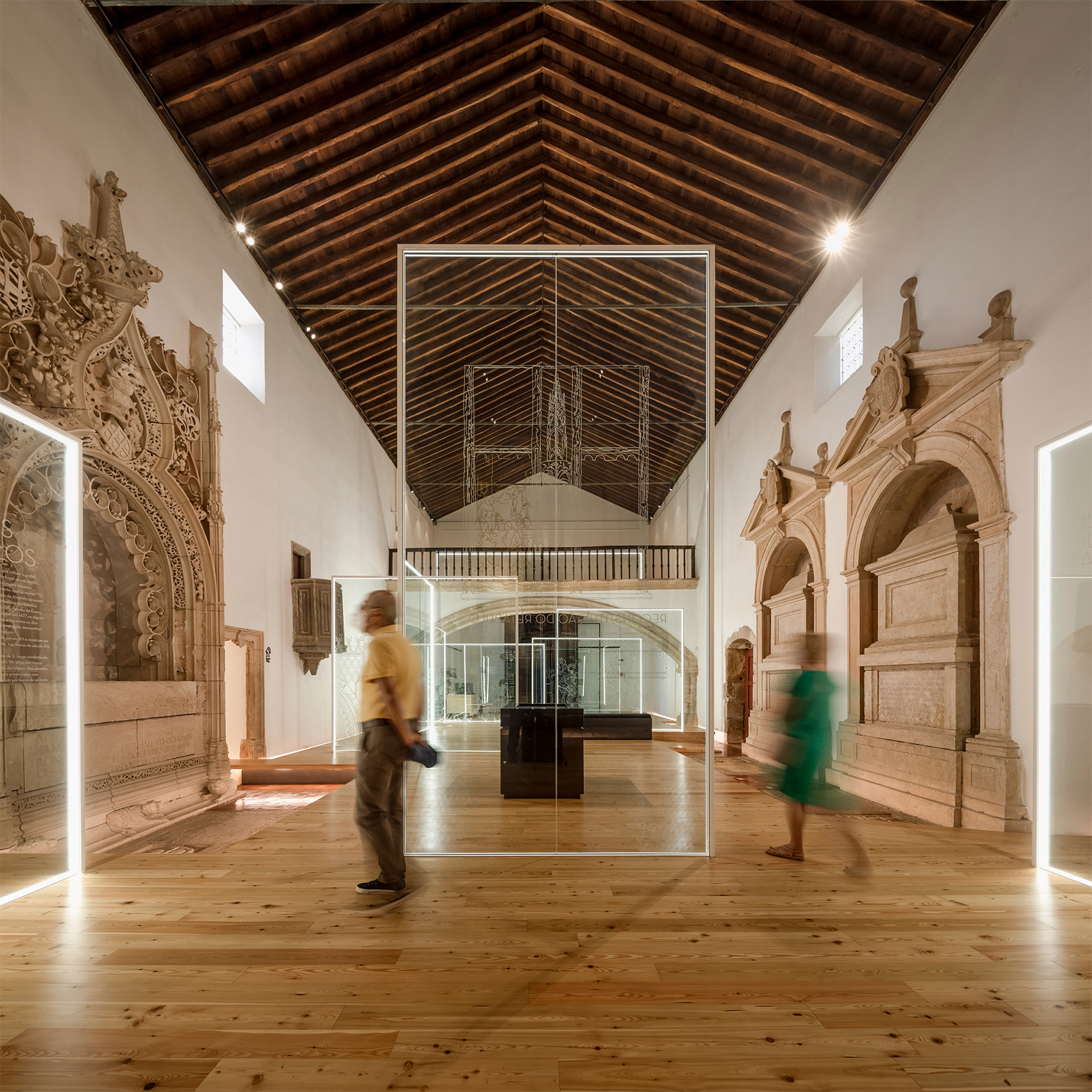 Panteão dos Almeida, Abrantes: visitors walking among the glass structures beneath the timber ceiling of the nave