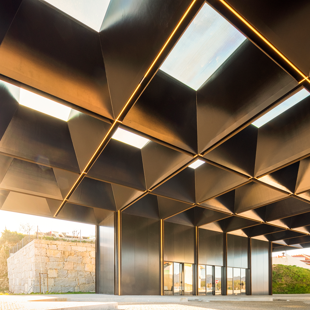 Lousada Intermodal Hub: close view of the coffered ceiling with skylights, the glazed waiting room set below the grid