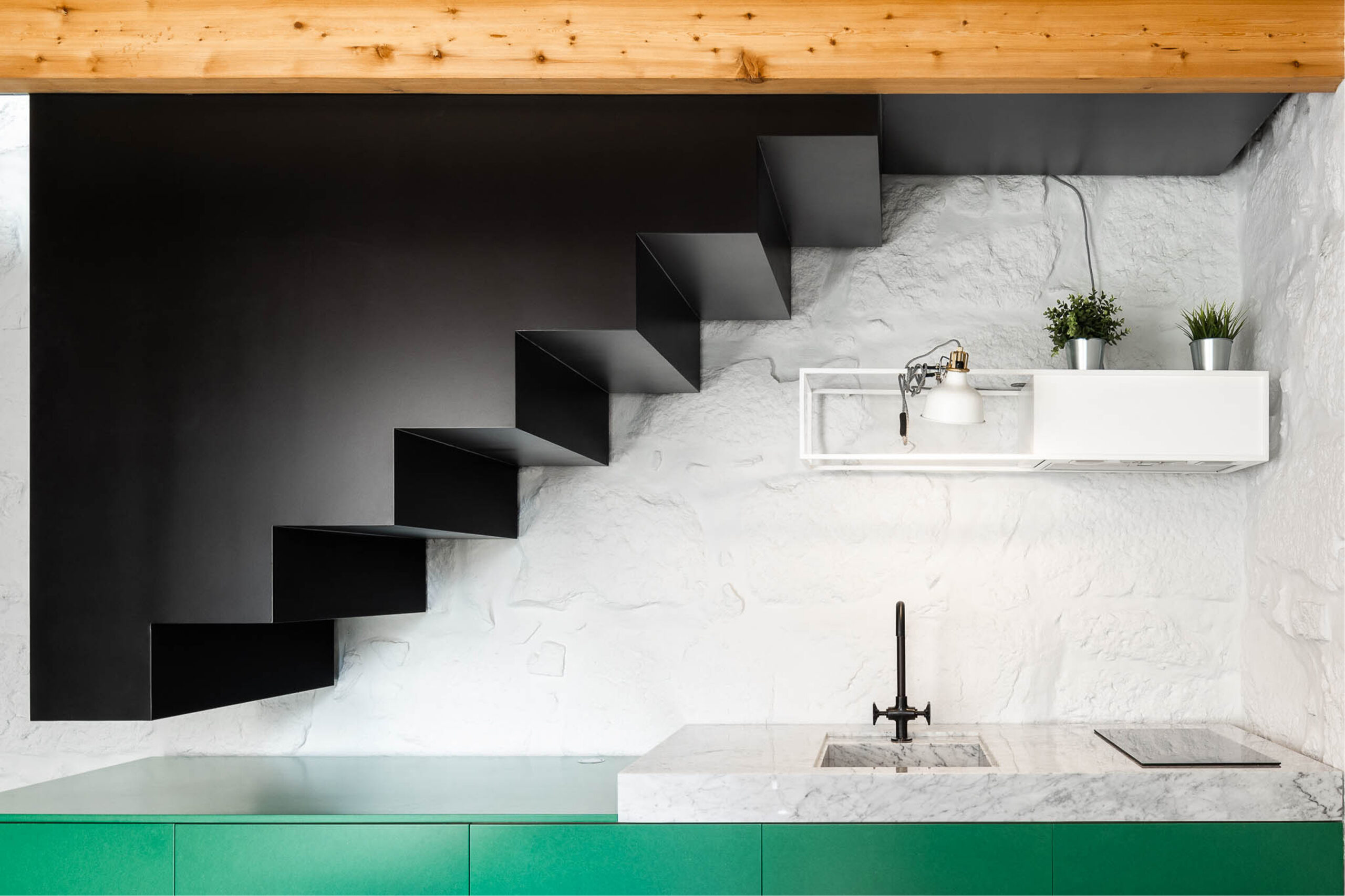 Covelo House, Porto: front view of the stair and kitchen wall, black treads above a pale worktop and sink