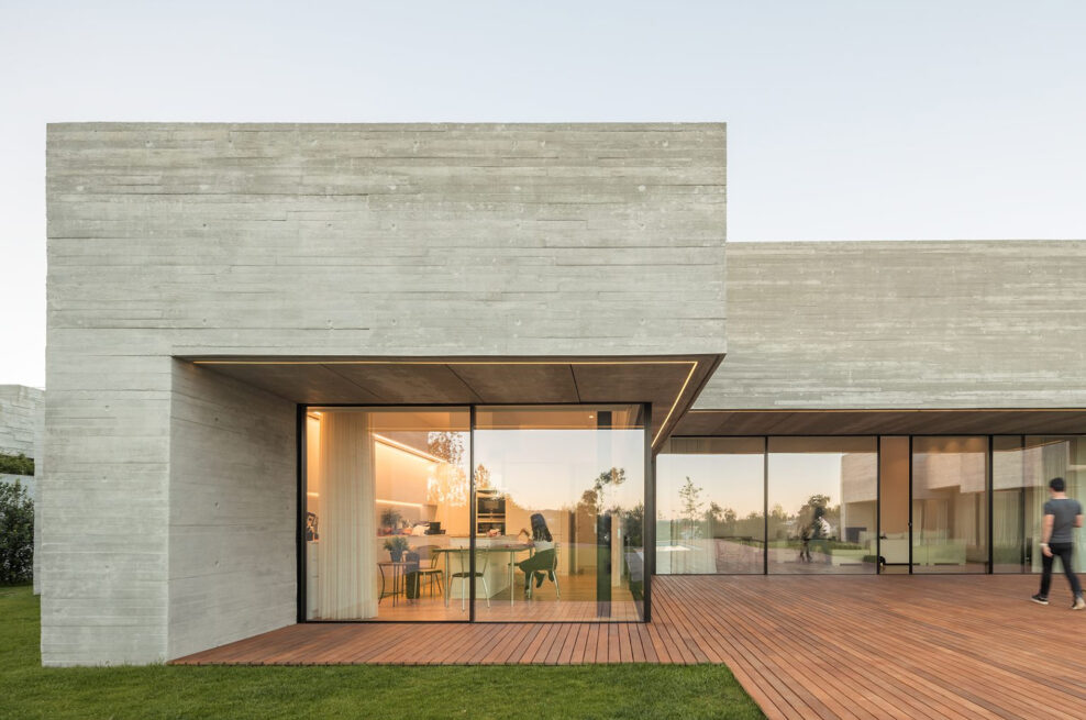 MF House, Paredes: glazed corner of the living area opening onto the deck, with a person walking outside