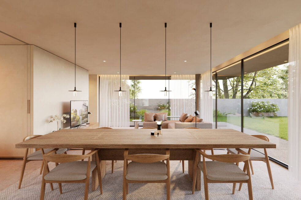 Dining table with wooden chairs facing wide glazing onto the garden of Avanca House