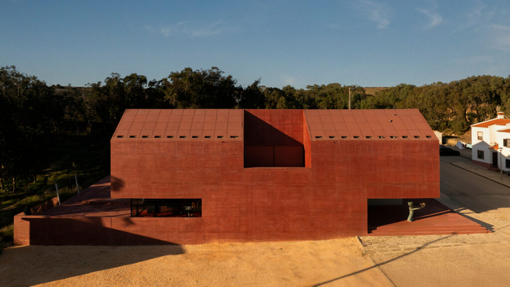 Elevated view of the red pigmented concrete volume of the Vila do Bispo Museum in the Algarve against pine woodland