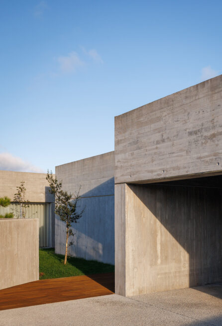 FS House, Paços de Ferreira: recessed entrance carved into the concrete volume, with a wooden deck at its threshold