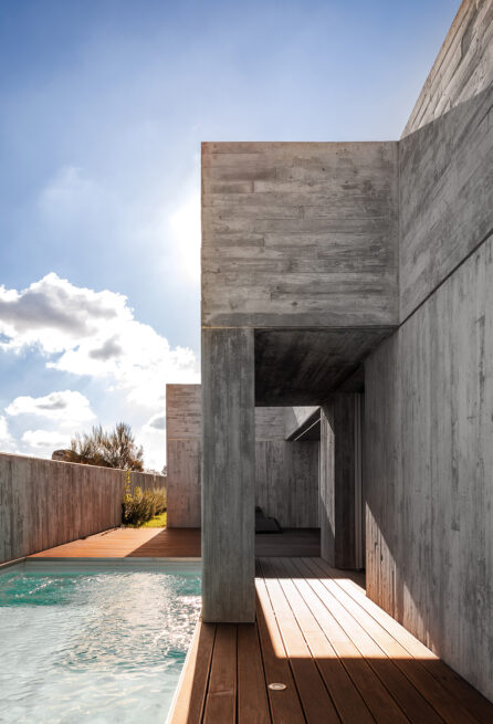 FS House, Paços de Ferreira: covered passage between concrete volumes opening onto the pool and wooden deck