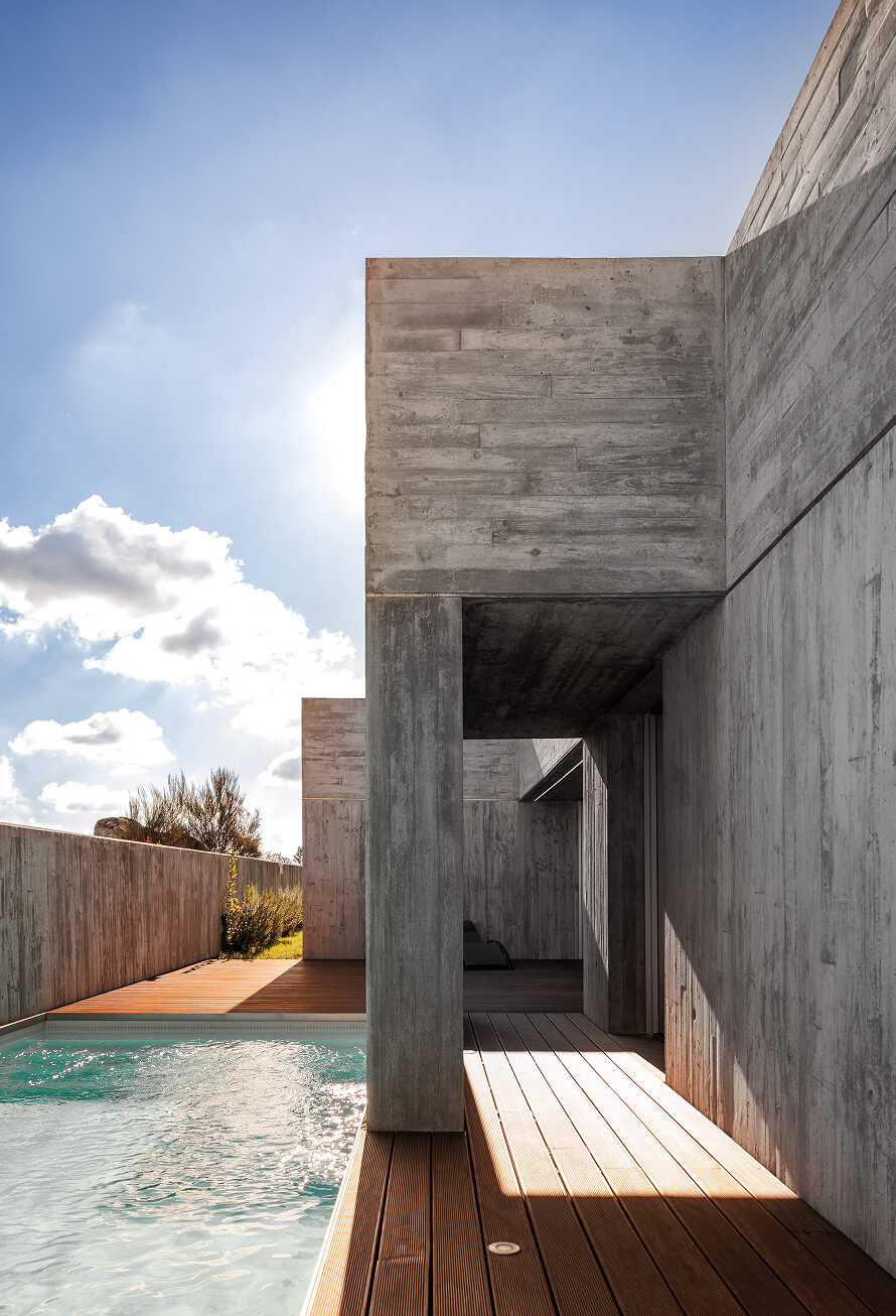 FS House, Paços de Ferreira: covered passage between concrete volumes opening onto the pool and wooden deck