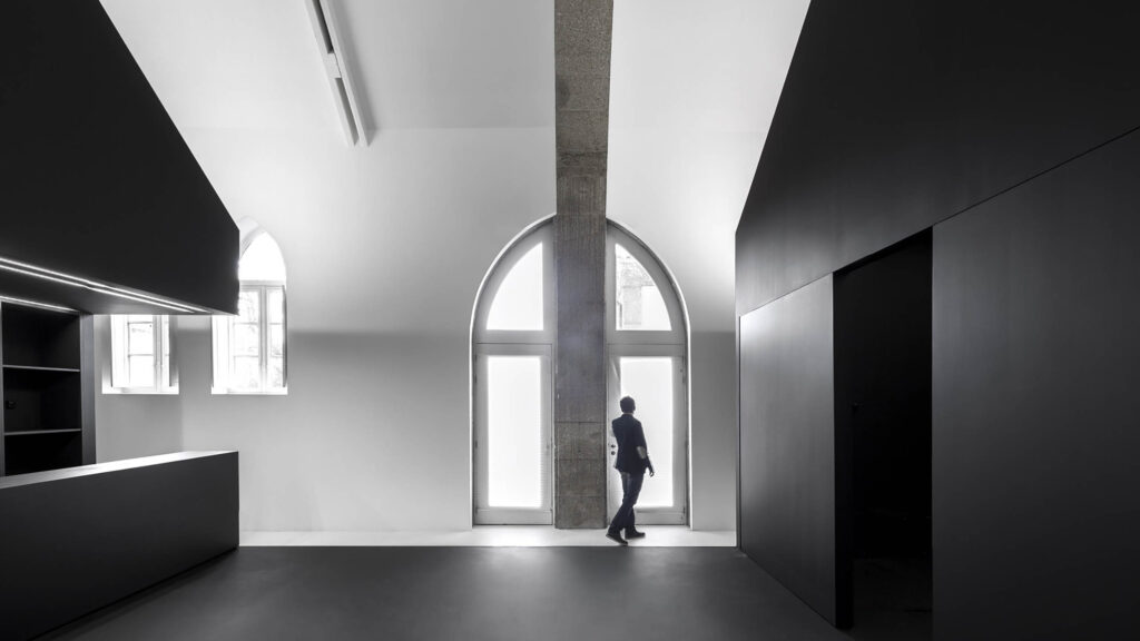 Information Centre of the Romanesque Route, Paredes: white interior with an arched window and a black inserted volume