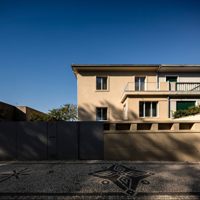 Combatentes House, Porto: street facade of the semi-detached house behind a dark gate, over Portuguese cobblestone pavement
