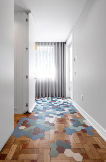 Combatentes House, Porto: white corridor with hexagonal tiles in blue, red and grey set into the wooden parquet