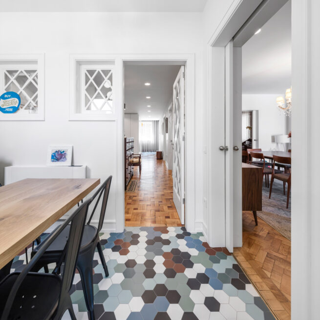 Combatentes House, Porto: dining area with a wooden table and black chairs, multicoloured hexagonal tiles leading to the corridor