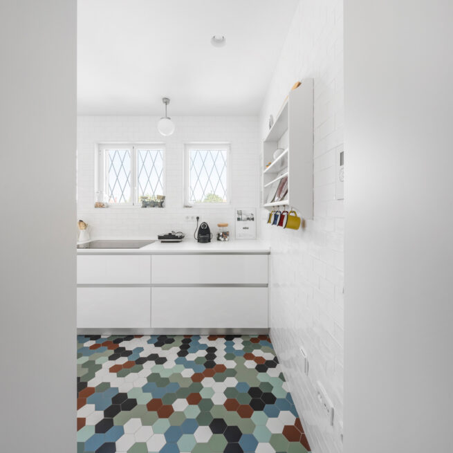 Combatentes House, Porto: white kitchen with diamond-pane windows and a floor of multicoloured hexagonal tiles