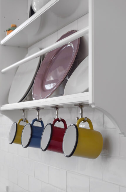 Combatentes House, Porto: detail of a white plate rack with coloured enamel mugs hanging below
