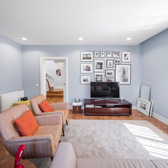 Combatentes House, Porto: living room with pale blue walls, two armchairs, a light rug and a gallery wall of framed pictures