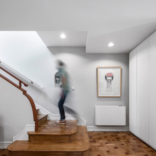 Combatentes House, Porto: person climbing the wooden staircase past white built-in cupboards