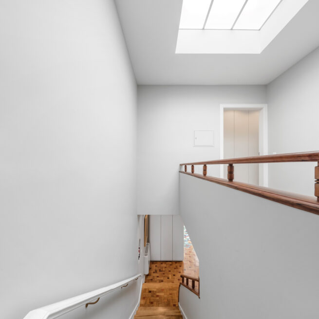 Combatentes House, Porto: stairwell under a skylight, white walls and a wooden handrail