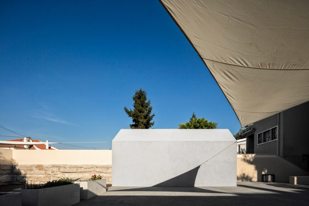 Combatentes House, Porto: house-shaped annex standing in the backyard beneath a beige shade sail