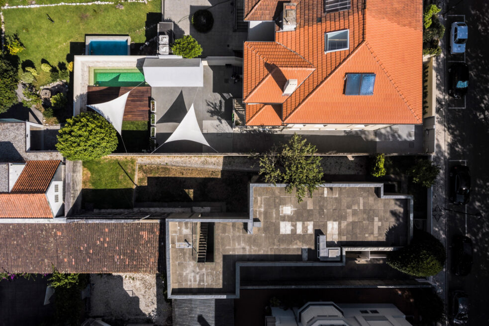 Combatentes House, Porto: aerial view of the house, its terracotta roof and the backyard with pool and white shade sails