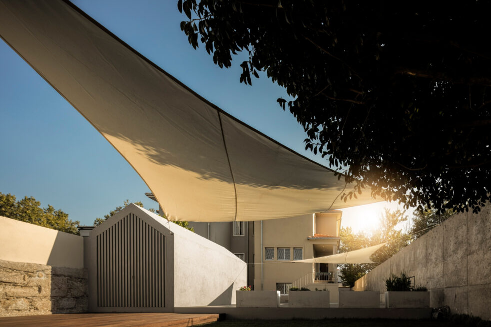 Combatentes House, Porto: low sun through a shade sail, the annex and the rear facade beyond