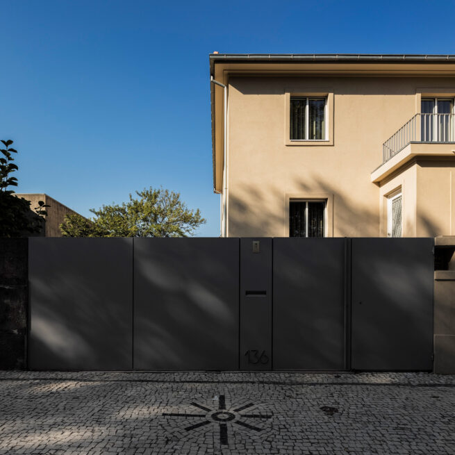 Combatentes House, Porto: street facade above the dark metal gate and a cobblestone pavement pattern