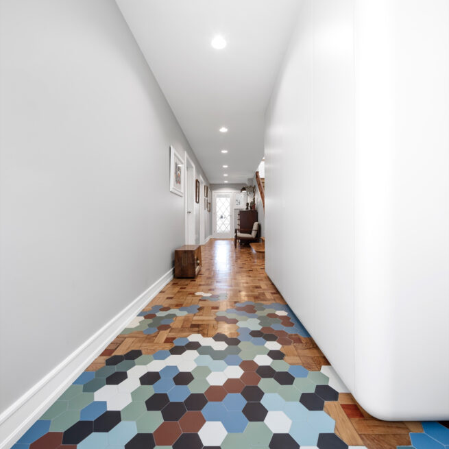 Combatentes House, Porto: long white corridor of the ground floor with a band of multicoloured hexagonal tiles