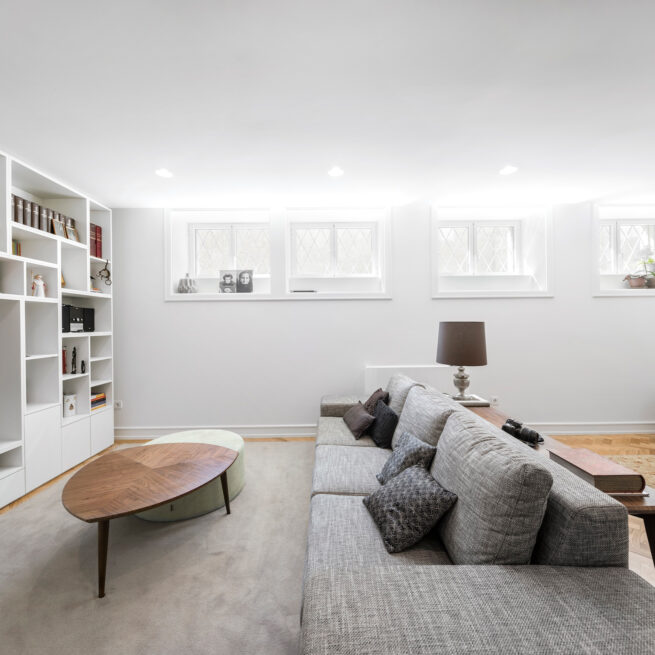Combatentes House, Porto: multipurpose room on the lower floor with bookshelves, a sofa and high windows