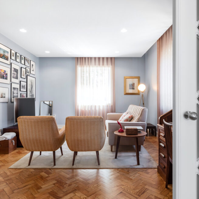 Combatentes House, Porto: living room with pale blue walls, two armchairs and framed pictures